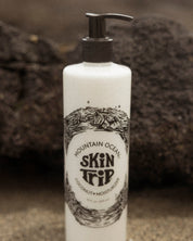 Lotion bottle with 'Mountain Ocean' and 'Skin Trip' branding on a textured surface.