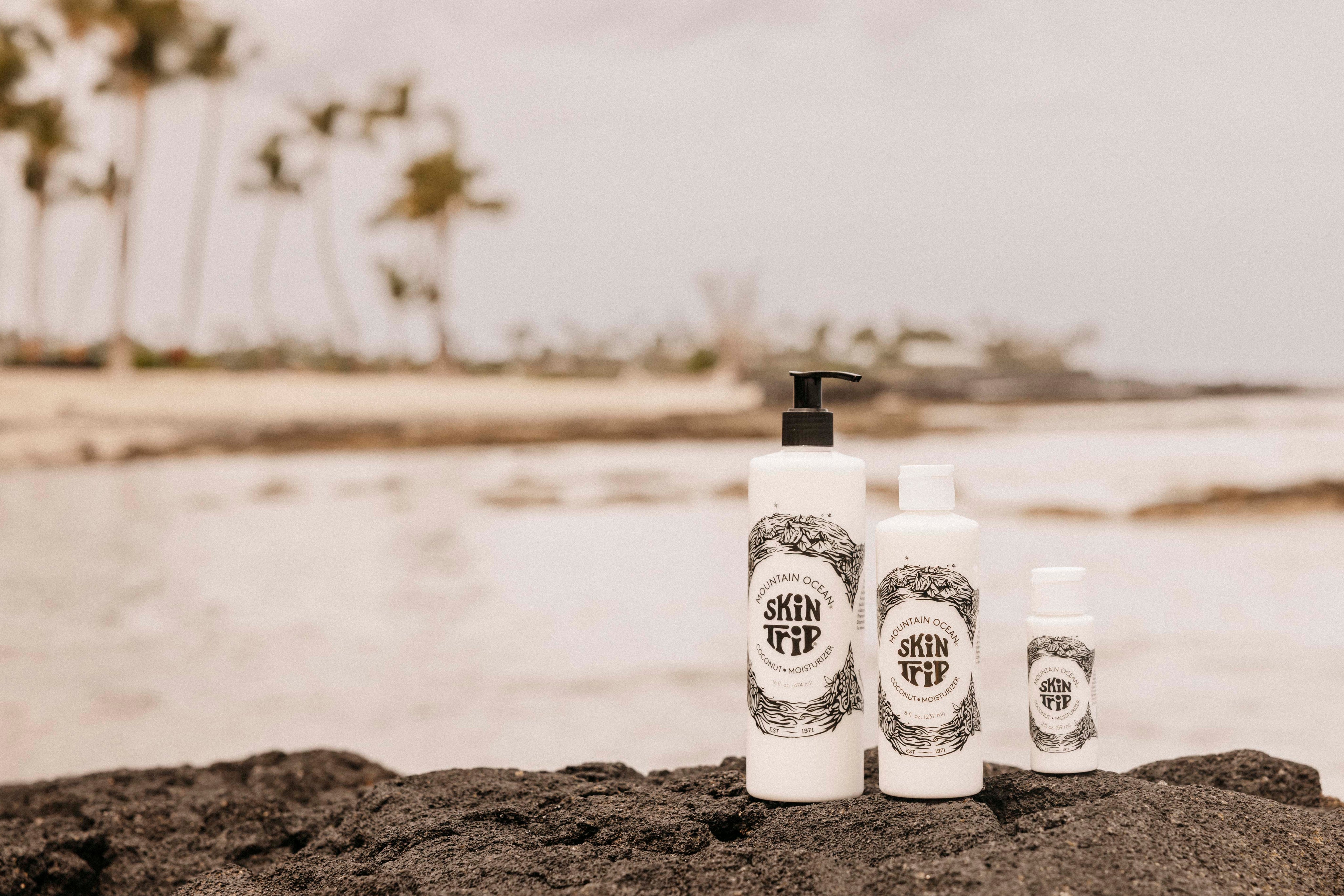 Skincare bottles with 'Satin Off' branding on a beach.
