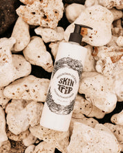 Skincare product bottle labeled 'Skin Deep' on a rocky surface