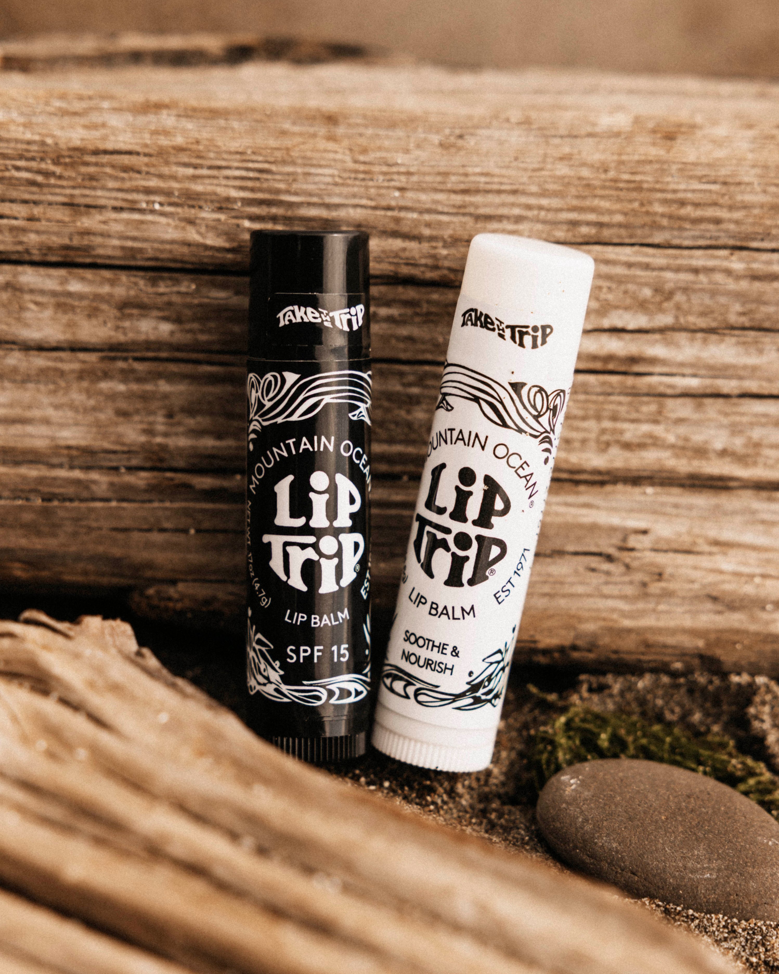 Two lip balm tubes on a wooden surface with a natural background