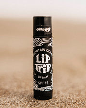 Lip balm tube labeled 'Lip It' on a sandy surface
